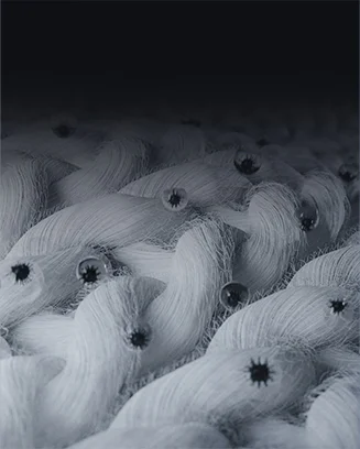 흰색 섬유들이 서로 엮여 있는 모습이 보입니다. 섬유 사이사이에 작은 물방울들이 맺혀 있으며, 이 물방울들은 빛을 반사하여 반짝이는 효과를 나타내고 있습니다. 섬유의 질감과 물방울의 배치가 강조된 이미지입니다.